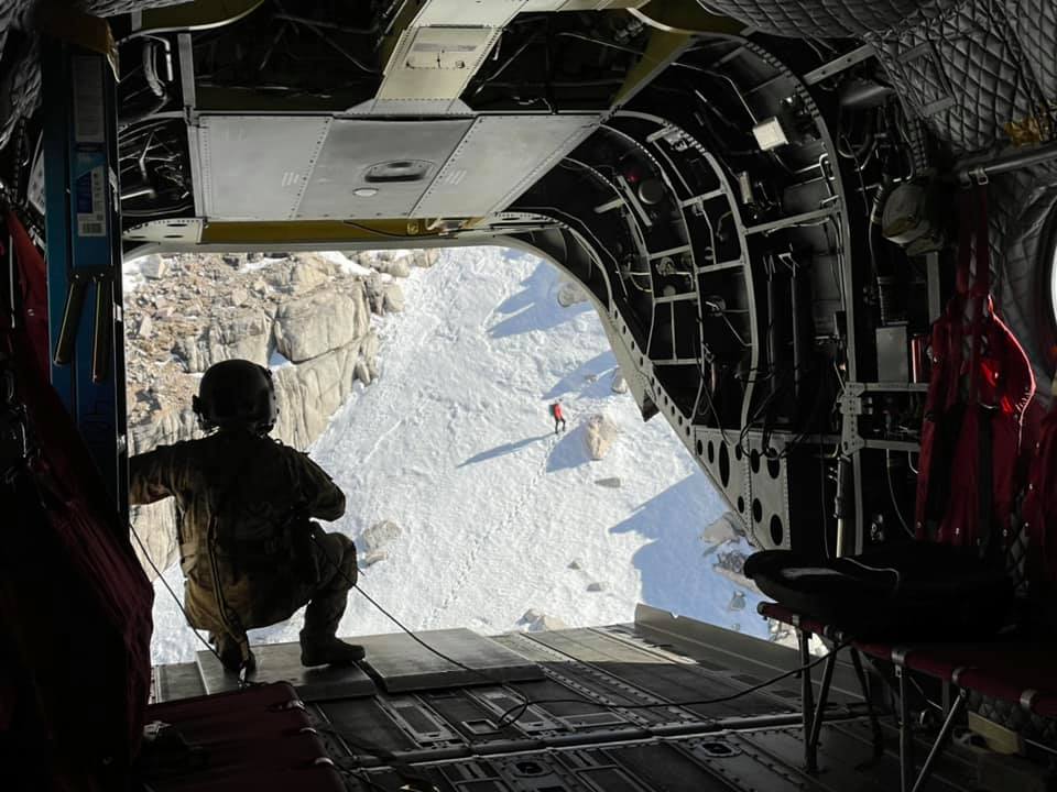 View looking out of Chinook helicopter towards deep gorge snow covered chute